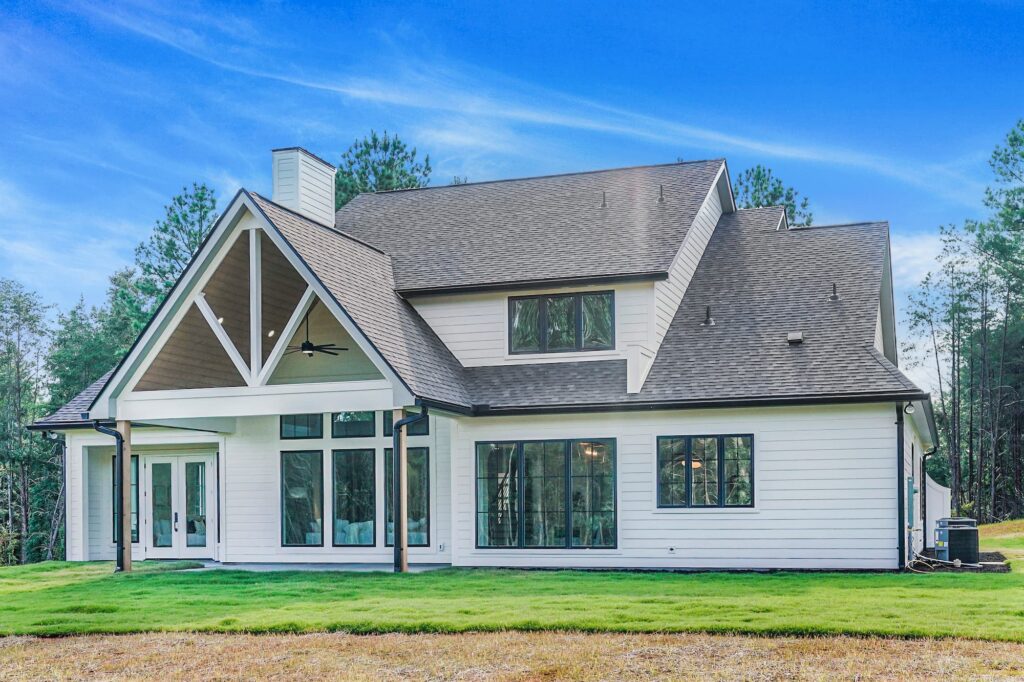 Back exterior with covered porch and steep gable roofline of a Greenville semi-custom home