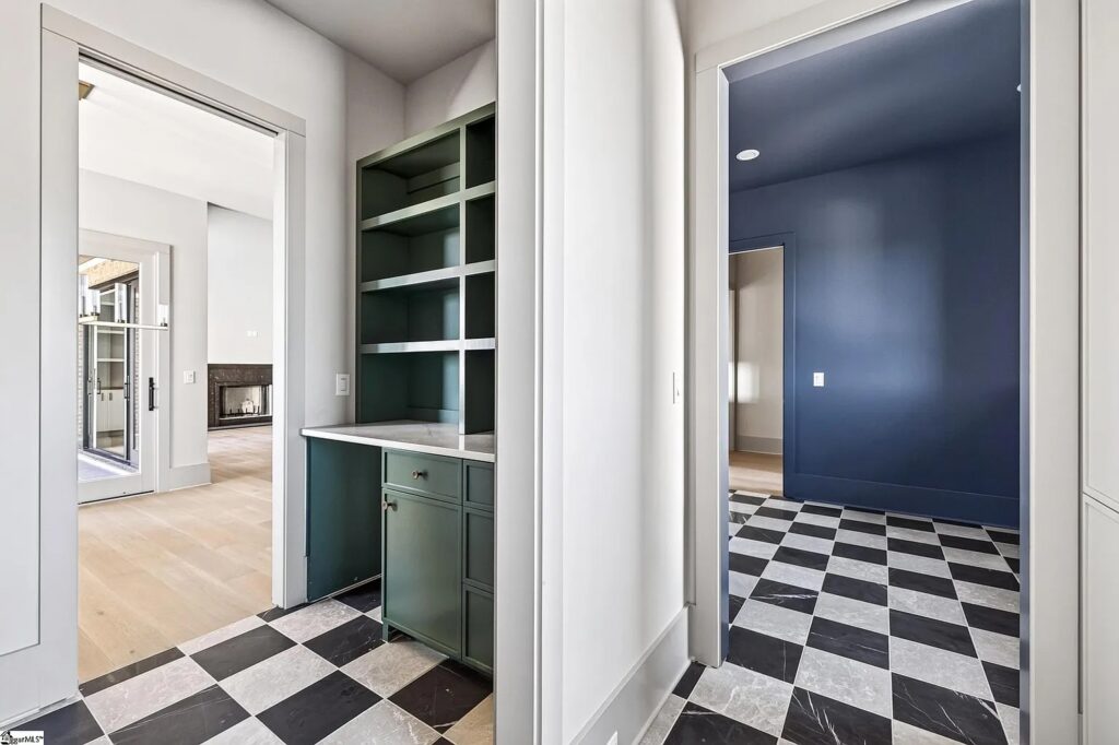 Scullery with deep green cabinetry and open shelving next to the kitchen