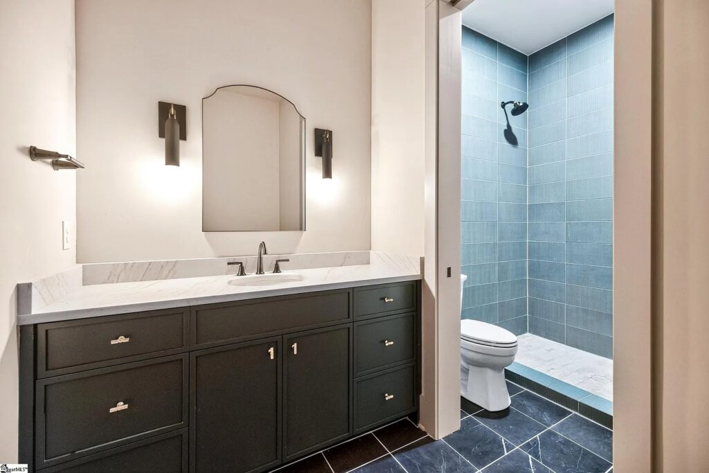 Guest bath with dark vanity, arched mirror and tiled walk-in shower