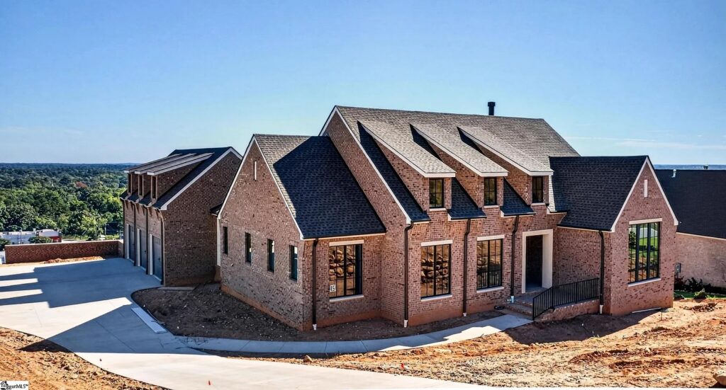 Brick new build home with steep gables, dormers and black-framed windows on a hillside in Greenville, SC