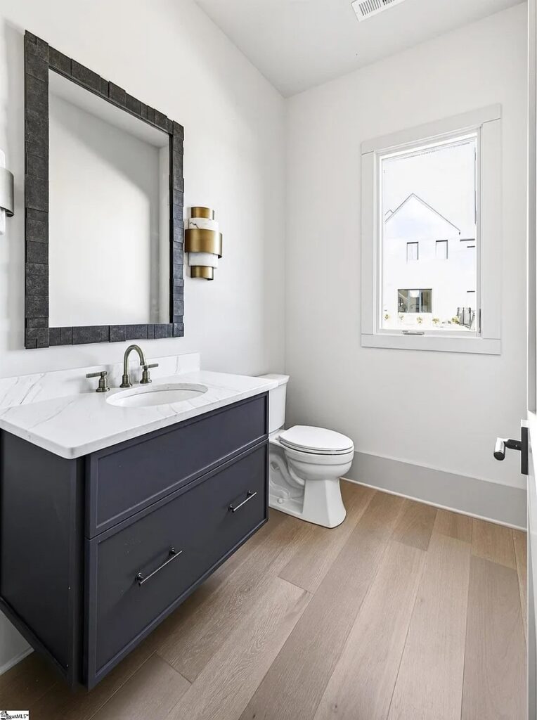 Powder bath with navy vanity, textured mirror and brass sconces