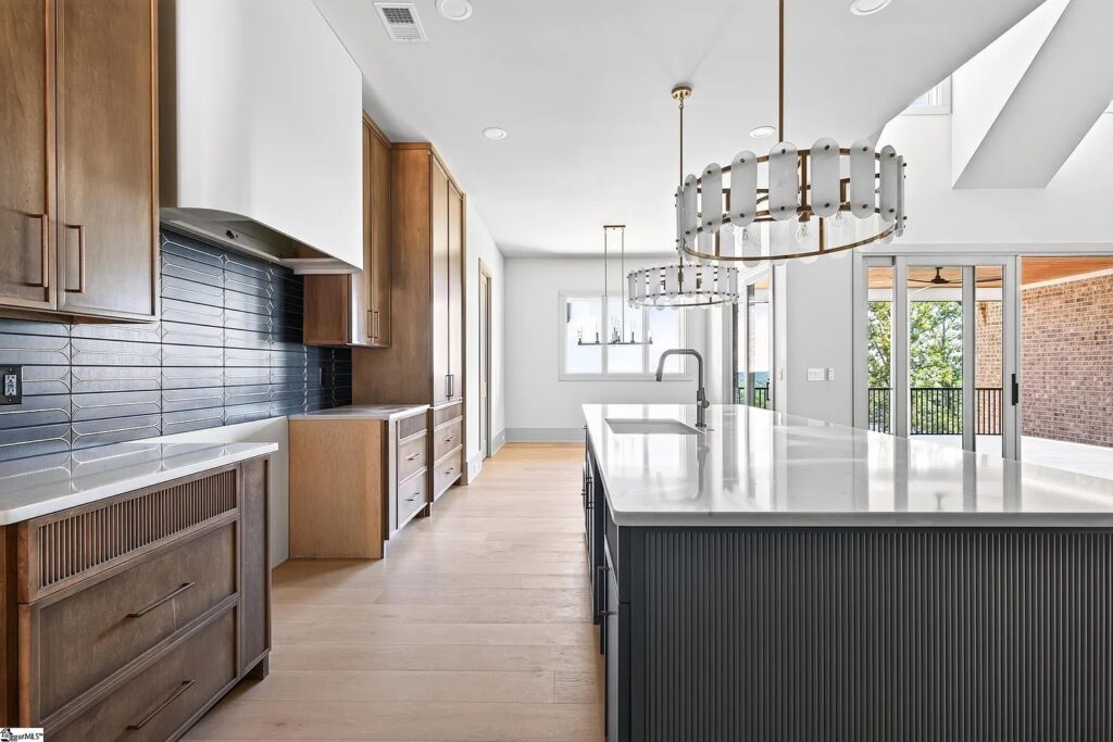Deep green fluted kitchen island with stacked tile backsplash and crystal chandelier